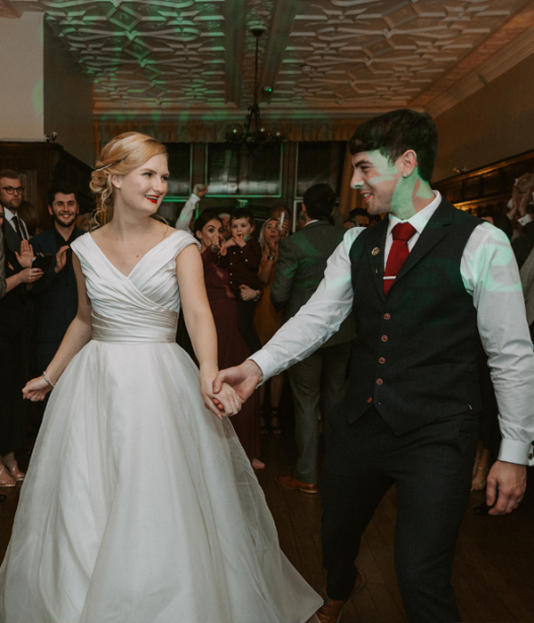 Bride and groom dancing at their wedding reception, surrounded by family.