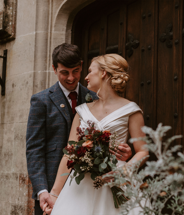 Bride and Groom standing outside a large wooden door