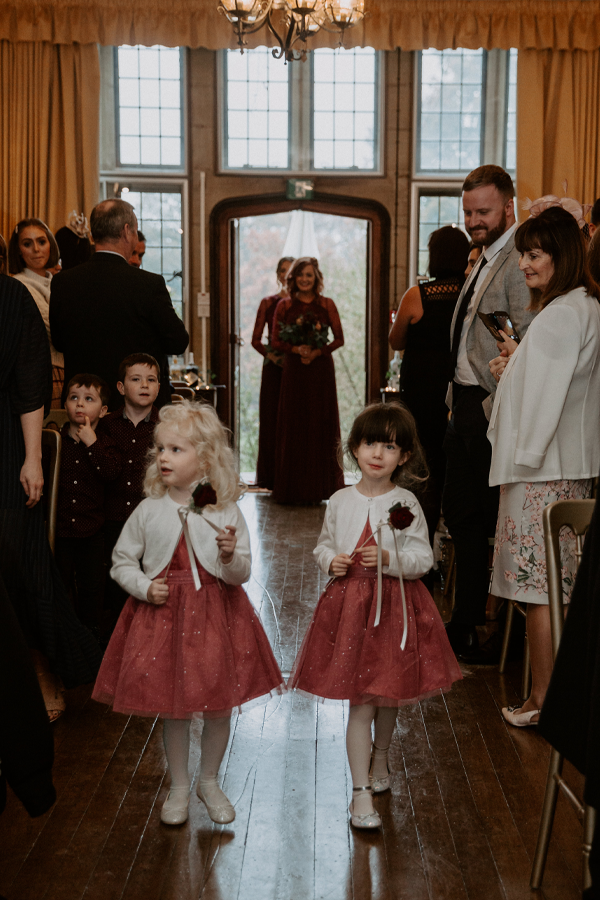 A crowd of wedding guests watching the wedding party enter through a door at the back of the room