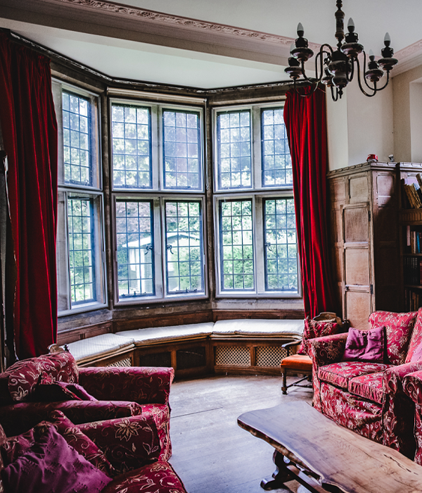 A room with red curtains, sofas and a table.