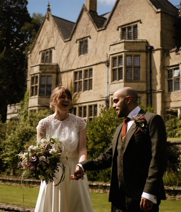 Wedding couple standing on lawn with a large building in the background