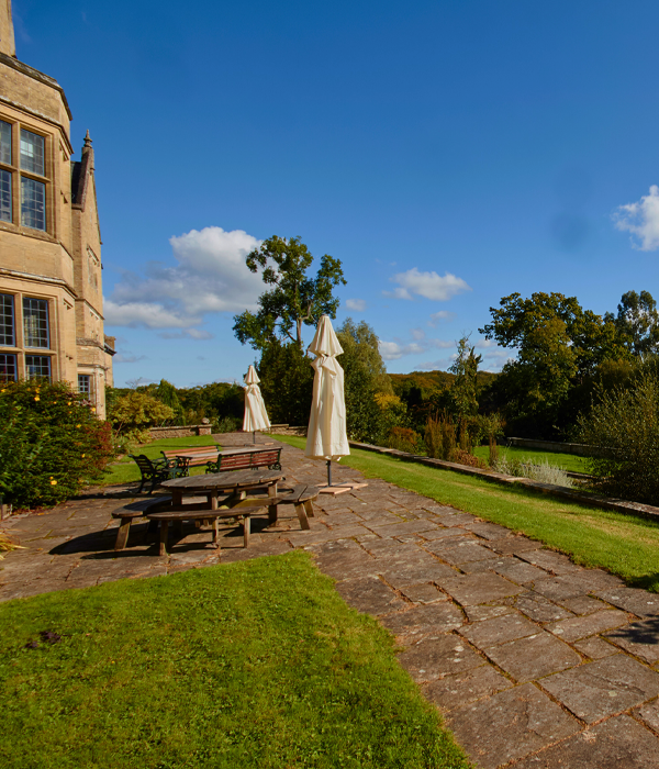 A summers view of a garden with a bench and parosoles.