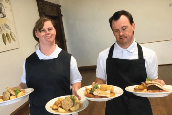 Two people holding dinner plates, ready to serve at an event held at Minstead Lodge.