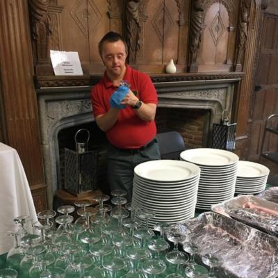 Two people preparing a table for a conference in the Long Hall at Minstead Lodge.