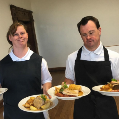 Two people holding dinner plates, ready to serve at an event held at Minstead Lodge.